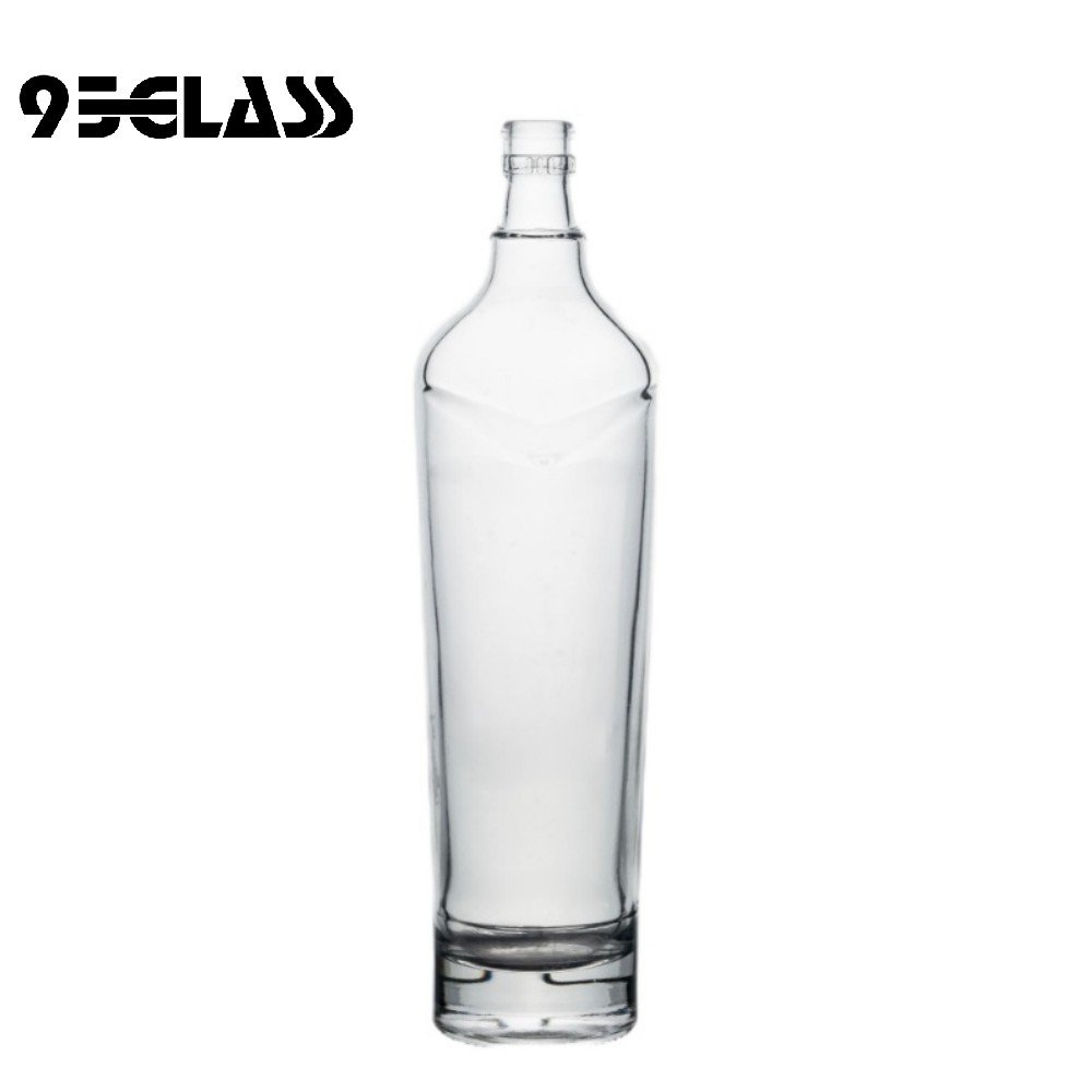 Tall crystal-clear glass whiskey bottle with modern shoulder design for premium spirits.